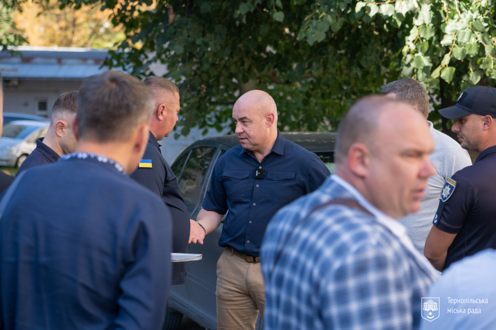 На фото група чоловіків стоїть на вулиці біля автомобілів. У центрі зображення міський голова Тернополя Сергій Надал - спілкується з іншими учасниками навчання. 