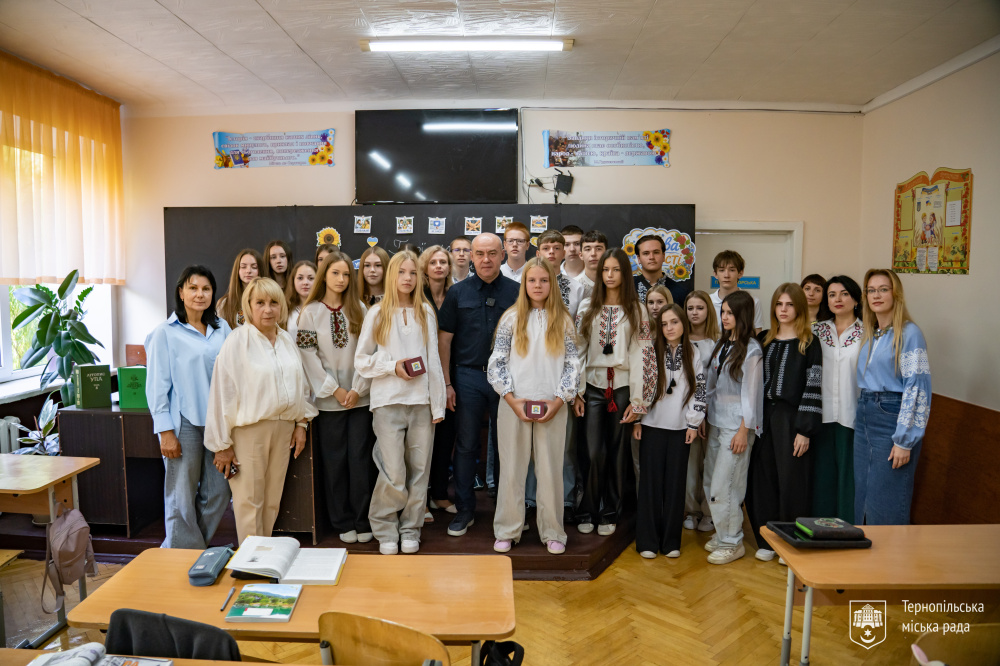 Міський голова Сергій Надал, школярі та вчителі стоять разом у класі після уроку. Дві дівчини тримають пам’ятні годинники.