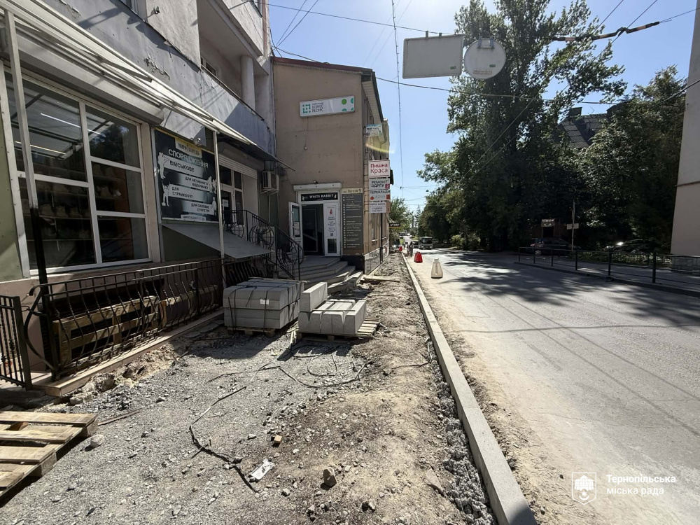 На розритому для ремонту тротуарі біля міських будівель складено піддони з новою бруківкою, а вздовж дороги вже встановлено сірий бордюр.