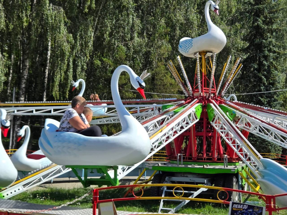 Діти катаються на атракціоні у вигляді білих лебедів